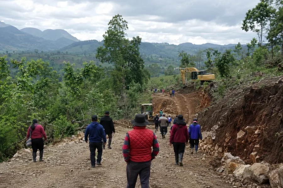 Camino rural con maquinaria y habitantes durante jornada comunitaria de obras en los Altos de Chiapas