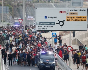 Policías y militares escoltan a un grupo de personas en Ceuta