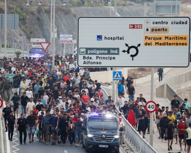 Policías y militares escoltan a un grupo de personas en Ceuta