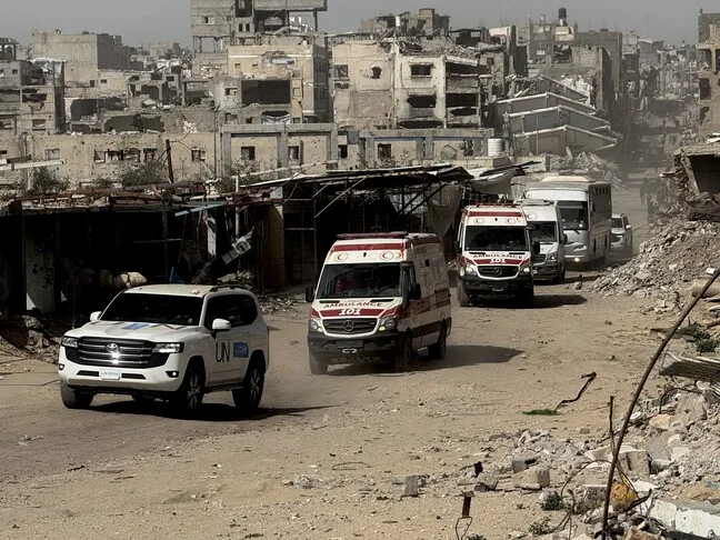 Vehículos de asistencia internacional circulan entre edificios dañados en los territorios palestinos